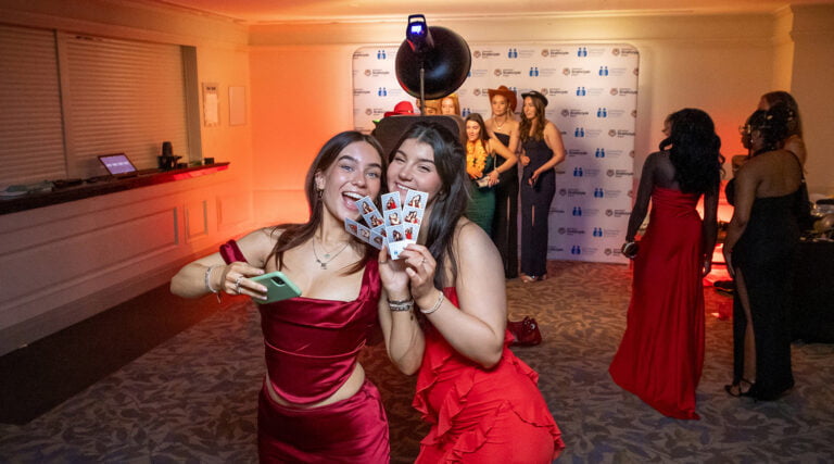 Two gils posing with instant photo booth prints